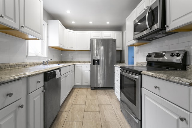 kitchen with stainless steel appliances, a sink, and white cabinets