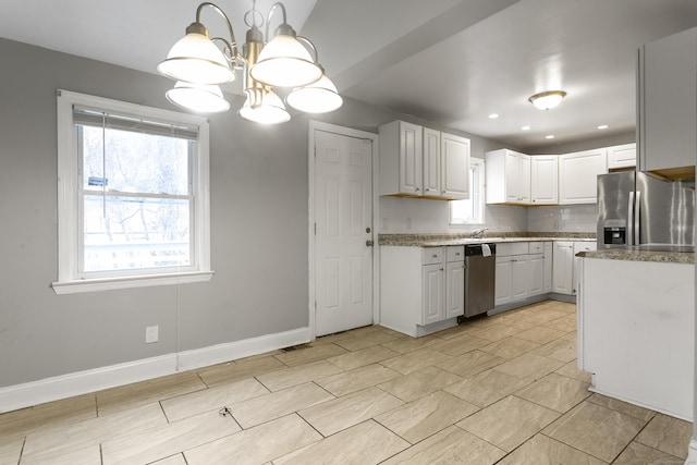 kitchen featuring baseboards, hanging light fixtures, light stone countertops, stainless steel appliances, and white cabinetry