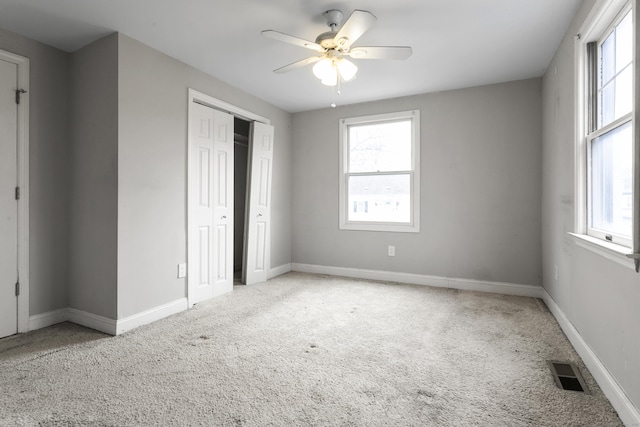 unfurnished bedroom with carpet, visible vents, and multiple windows