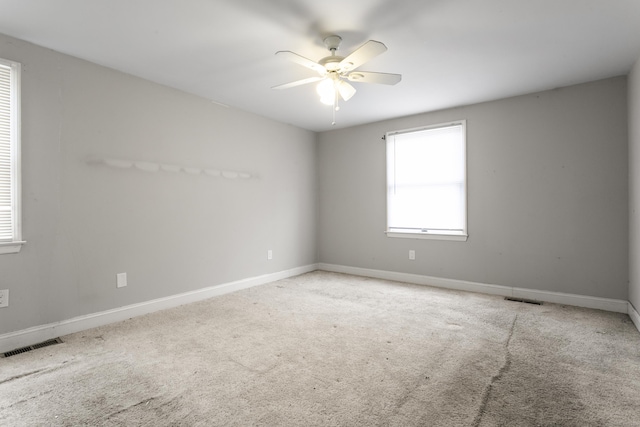 carpeted spare room featuring a ceiling fan, visible vents, and baseboards