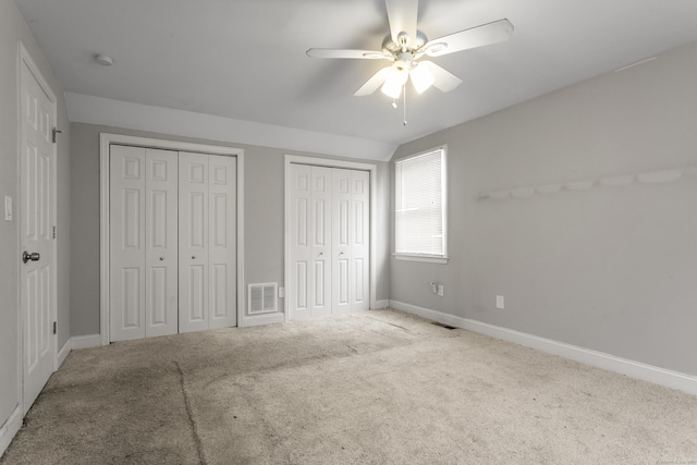 unfurnished bedroom with multiple closets, carpet, visible vents, and baseboards