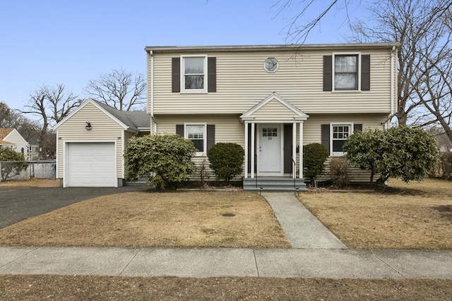 colonial home with aphalt driveway, a garage, and fence