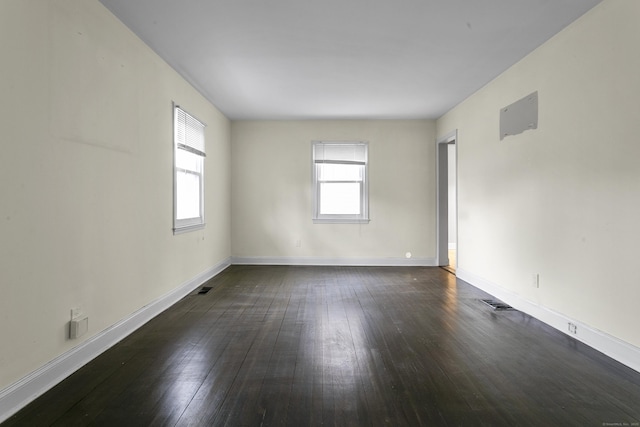 unfurnished room with dark wood finished floors, visible vents, and baseboards