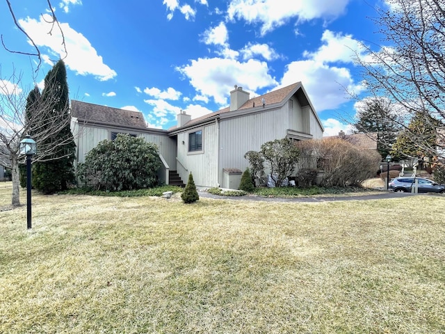 view of side of home featuring a chimney and a lawn