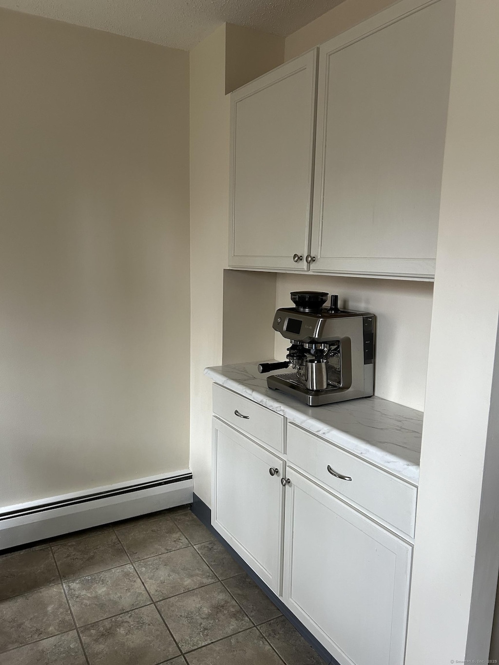 bar featuring a baseboard heating unit and dark tile patterned floors