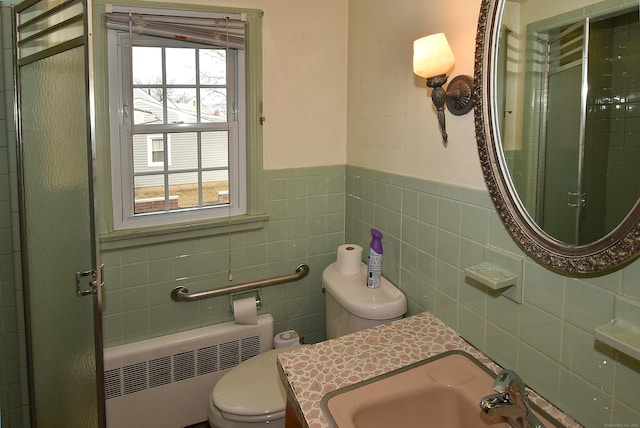 full bath with toilet, a shower with door, radiator heating unit, and a sink