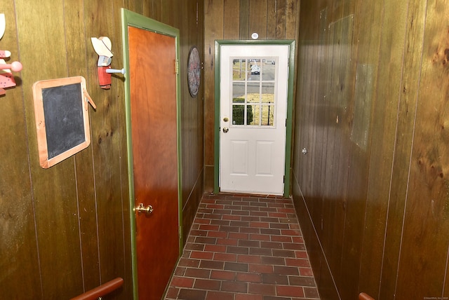 entryway featuring wood walls and brick floor