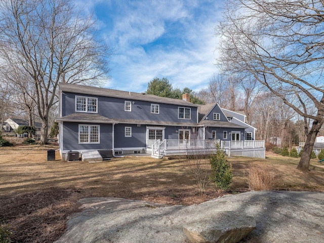 view of front of house with a deck, a chimney, central AC, and a front yard