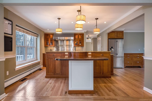 kitchen featuring light wood-type flooring, brown cabinetry, stainless steel refrigerator with ice dispenser, and a kitchen island