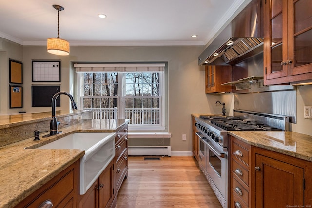 kitchen featuring a baseboard heating unit, double oven range, brown cabinets, wall chimney exhaust hood, and a sink