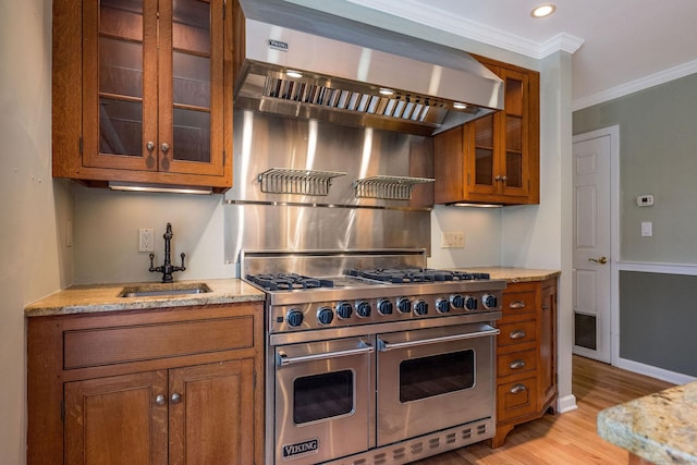 kitchen featuring brown cabinets, ornamental molding, a sink, range with two ovens, and light stone countertops