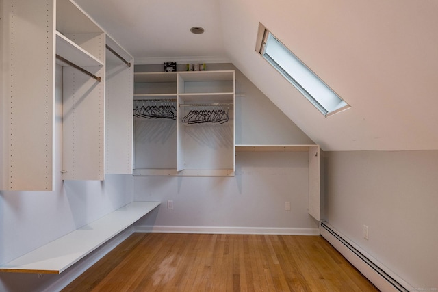 walk in closet featuring vaulted ceiling with skylight, wood finished floors, and a baseboard radiator