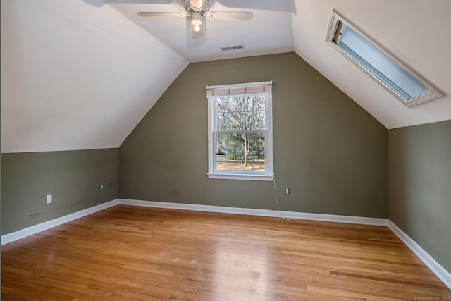 additional living space featuring visible vents, baseboards, vaulted ceiling with skylight, and light wood finished floors