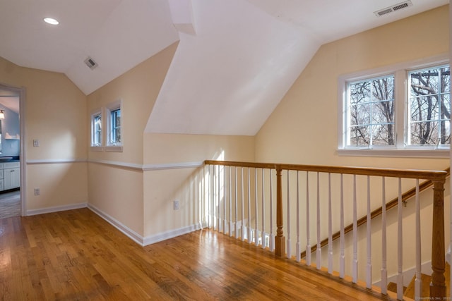 bonus room featuring vaulted ceiling, visible vents, baseboards, and wood finished floors