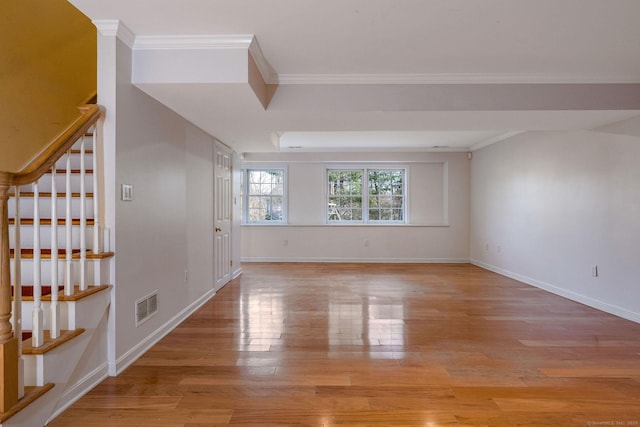 spare room with visible vents, baseboards, stairway, ornamental molding, and light wood-style floors