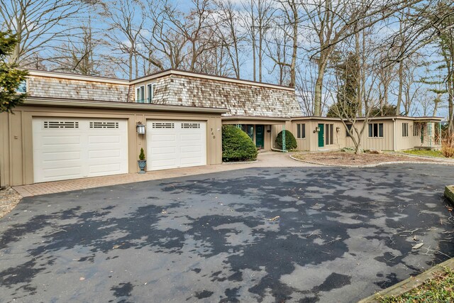 view of front of property with driveway, mansard roof, and a garage