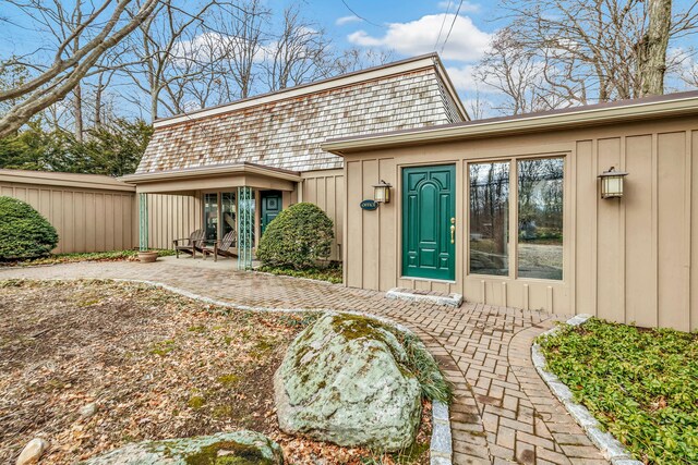 view of exterior entry with a patio, fence, and board and batten siding
