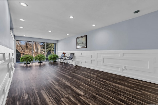 unfurnished room with dark wood finished floors, a wainscoted wall, recessed lighting, and a decorative wall