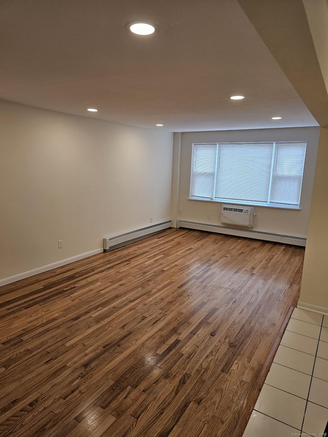 spare room featuring an AC wall unit, wood finished floors, recessed lighting, a baseboard radiator, and baseboards