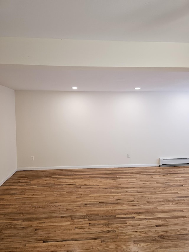 finished below grade area with recessed lighting, a baseboard heating unit, baseboards, and wood finished floors