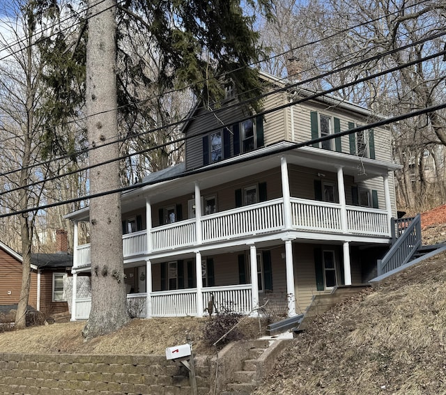 view of front of home featuring a balcony, a chimney, stairway, and a porch