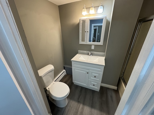 bathroom with vanity, baseboard heating, wood finished floors, and toilet