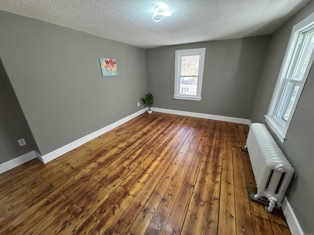 empty room with radiator, dark wood-style floors, and baseboards