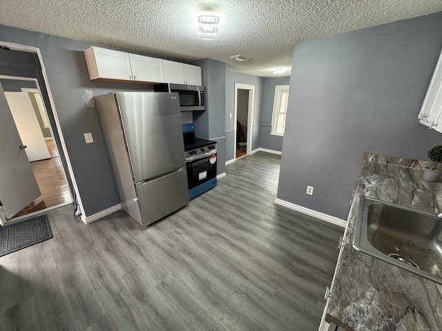 kitchen featuring baseboards, white cabinets, dark wood finished floors, stainless steel appliances, and a sink