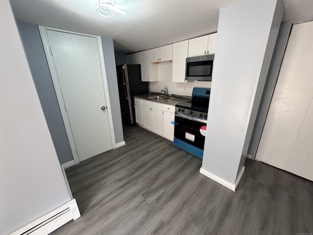 kitchen featuring a baseboard radiator, dark wood-type flooring, stainless steel appliances, white cabinetry, and a sink