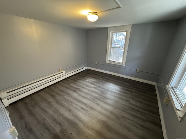 empty room with baseboards, baseboard heating, and dark wood-type flooring