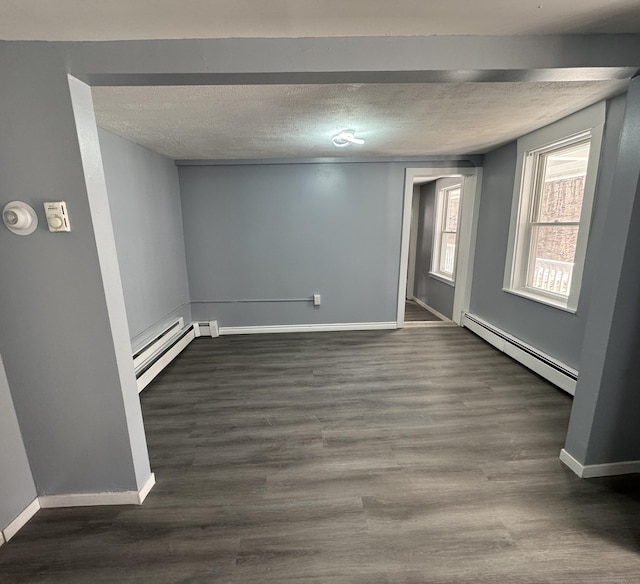 interior space with baseboard heating, a baseboard heating unit, dark wood-type flooring, a textured ceiling, and baseboards