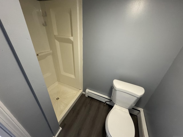 bathroom with toilet, a shower stall, baseboard heating, and wood finished floors