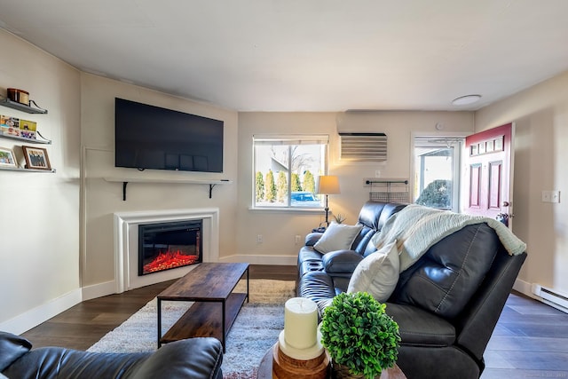 living area with a wealth of natural light, a glass covered fireplace, wood finished floors, and a wall unit AC