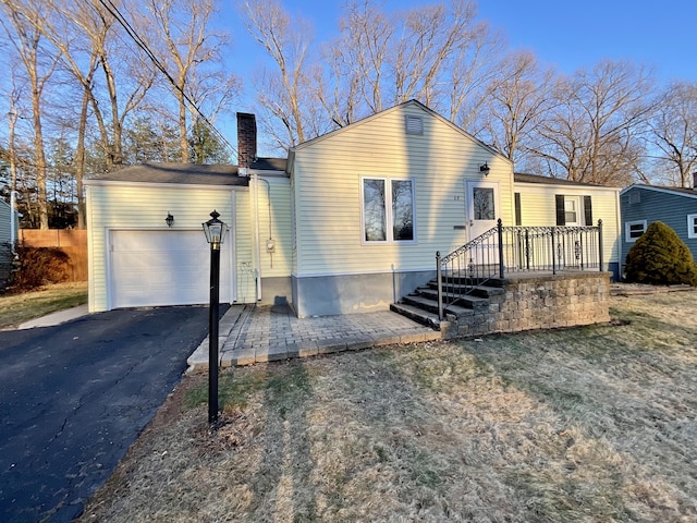 view of front of home with a garage, driveway, and a chimney