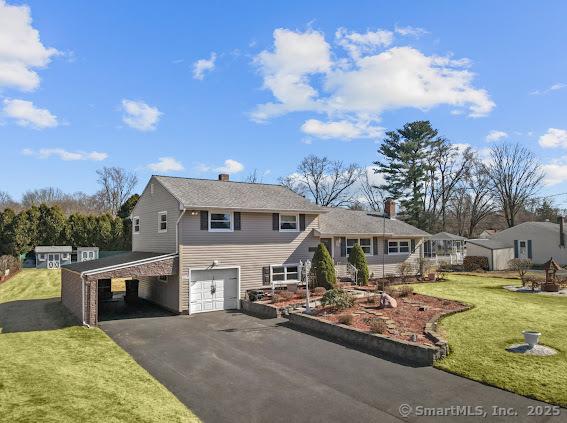 view of front of house featuring a carport, driveway, an attached garage, and a front yard