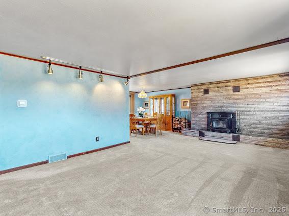 unfurnished living room featuring visible vents, carpet flooring, and baseboards