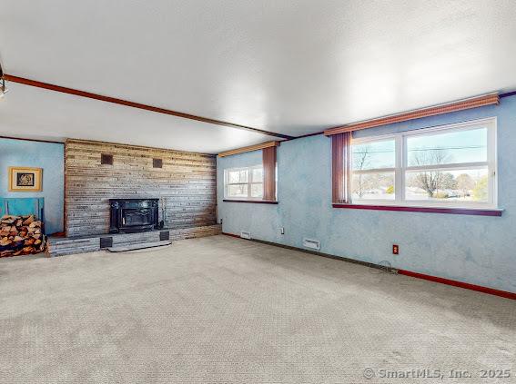 unfurnished living room featuring carpet flooring and baseboards