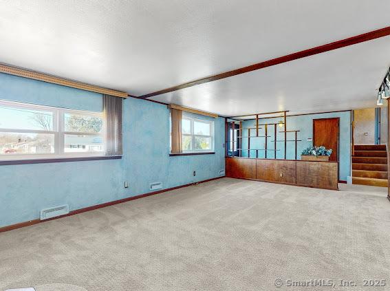 unfurnished room with stairway, visible vents, and carpet floors