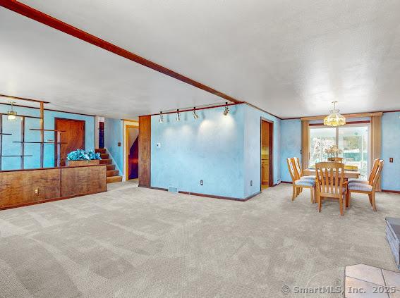 unfurnished dining area featuring stairway and carpet floors