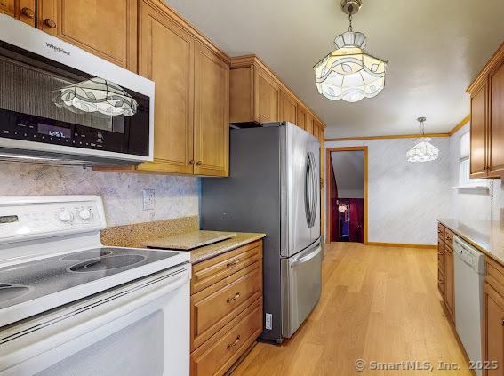 kitchen featuring light wood-type flooring, white appliances, hanging light fixtures, and light countertops