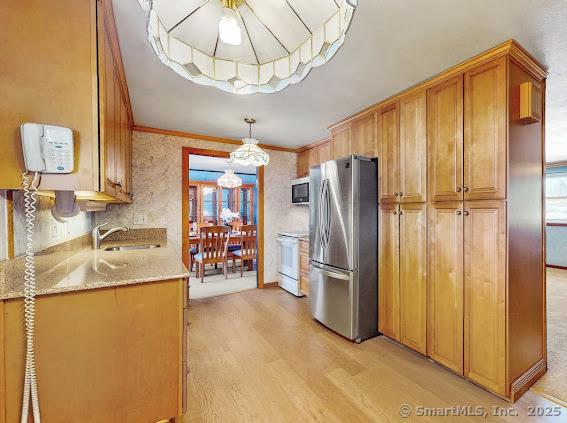 kitchen featuring white range with electric cooktop, freestanding refrigerator, a sink, light wood-style floors, and crown molding