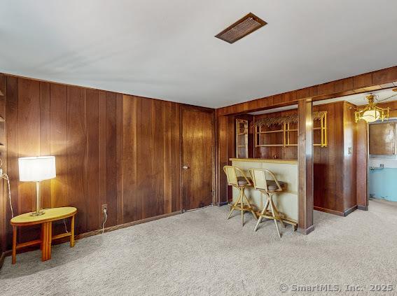 carpeted dining space with wood walls