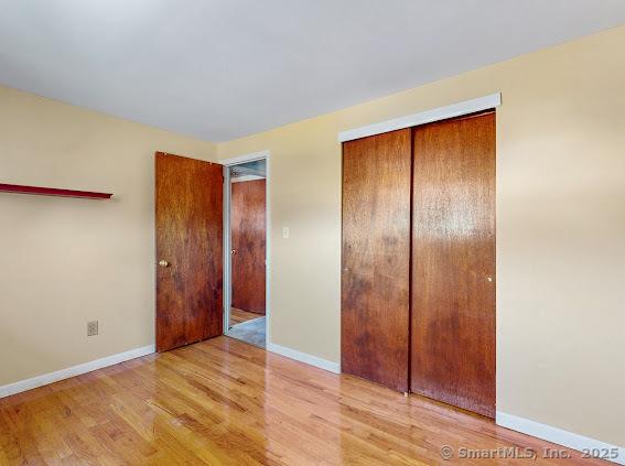 unfurnished bedroom featuring a closet, baseboards, and wood finished floors