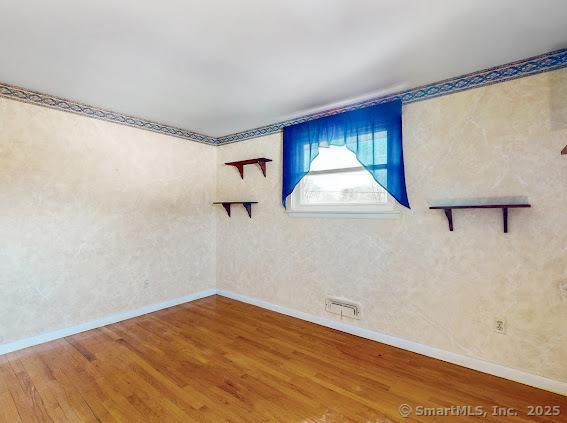 empty room with visible vents, wood finished floors, and baseboards