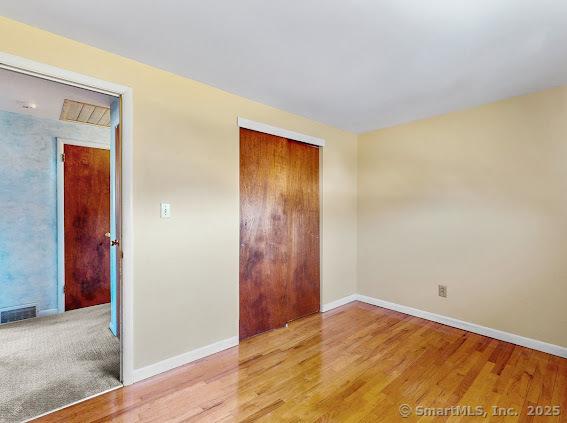 empty room featuring visible vents, baseboards, and wood finished floors