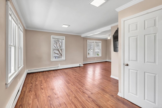 empty room with baseboard heating and crown molding