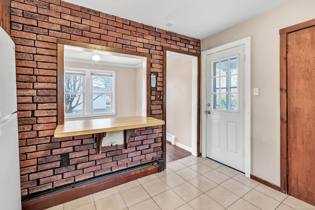 entrance foyer featuring brick wall, crown molding, light tile patterned floors, baseboards, and baseboard heating