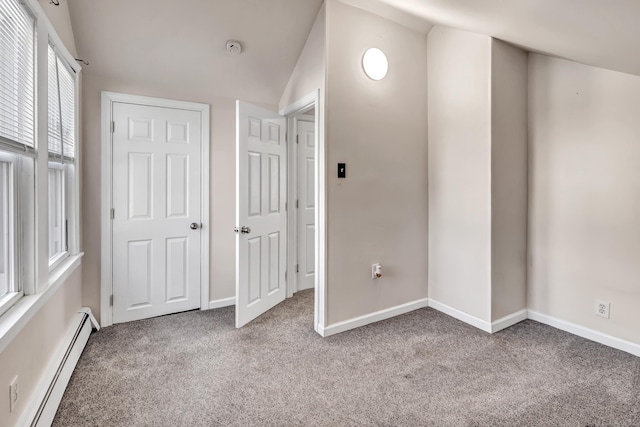 unfurnished bedroom with a baseboard heating unit, carpet flooring, and vaulted ceiling