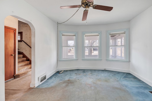 carpeted empty room with visible vents, plenty of natural light, baseboards, and stairs