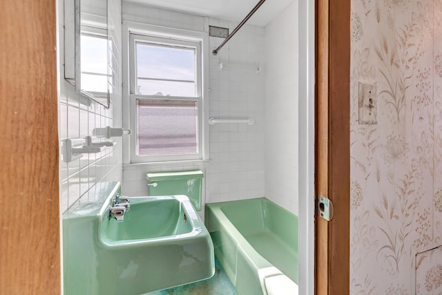 bathroom featuring bathtub / shower combination, tile walls, and a sink